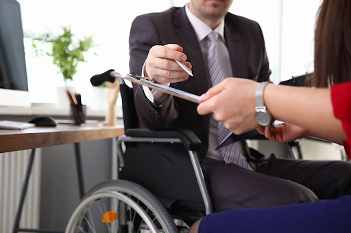 Man in wheelchair handing over a pen.