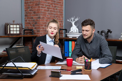 Two colleagues discussing documents in a cozy office setting.