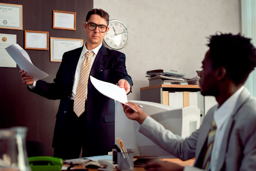 Two businessmen exchanging papers in office.